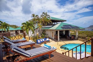 A poolside area with lounge chairs, a covered seating area, and a view of the ocean. - Hilltop 1-bed Villa with great views out to sea - Villa Cadasse (Cap Estate)