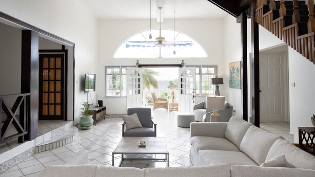 Amplia sala de estar con un gran ventanal, una escalera y vistas al exterior.