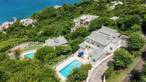 An aerial view of a coastal property with multiple houses, a swimming pool, and lush greenery. - Brise De Mer * 2-bed villa with captivating views of the Caribbean Sea (Cap Estate)