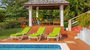 A pool area with three green lounge chairs, a covered seating area, and a view of a lush garden. - Villa Decaj - Beautiful 2 bedroom Villa with private pool in Cap Estate (Cap Estate)