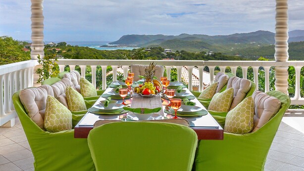 A dining table set for four with green upholstered chairs, a fruit bowl, and wine glasses. - Villa Decaj - Beautiful 2 bedroom Villa with private pool in Cap Estate (Cap Estate)