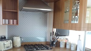 A compact kitchen with wooden cabinets, a gas stove, a toaster, and a microwave.