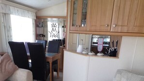 A living room with two sofas, a dining table, and wooden cabinets.