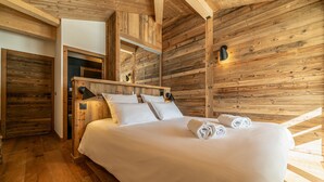 A wooden-paneled bedroom with a large bed, a mirror, and a nightstand. - Duplex Pen Men - LES GETS: close to the center, hot tub, superb view (Les Gets)