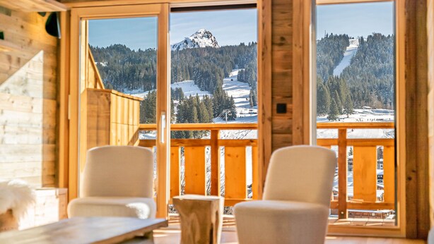 A wooden cabin with large windows offering a view of a snowy mountain and forest. - Duplex Pen Men - LES GETS: close to the center, hot tub, superb view (Les Gets)