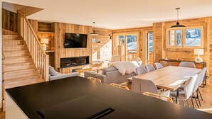 A modern log cabin interior with a wooden staircase, a dining area, and large windows offering a view of a snowy landscape. - Duplex Pen Men - LES GETS: close to the center, hot tub, superb view (Les Gets)