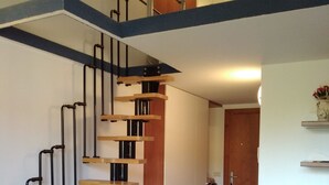 Un appartement moderne avec un escalier en bois, un canapé bleu et un coin repas.