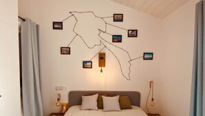 Quarto com uma cama grande, luminária na parede e várias fotos emolduradas.