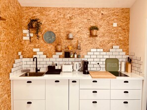 Een keuken met witte kastjes, een zwart aanrecht, een klok en een koffiezetapparaat.