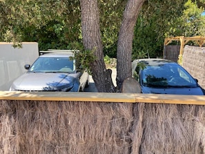 A parking area with two cars, a tree, and a wooden fence.
