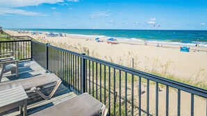 A beach view from a balcony with a wooden deck, lounge chairs, and a railing. - Oceanfront 3BR | Indoor & Outdoor Pools + Hot Tub | Pet Friendly | Elevator (Kill Devil Hills)