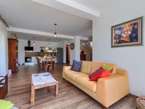Un salon spacieux avec un canapé, une table basse et un coin repas à l’arrière-plan.