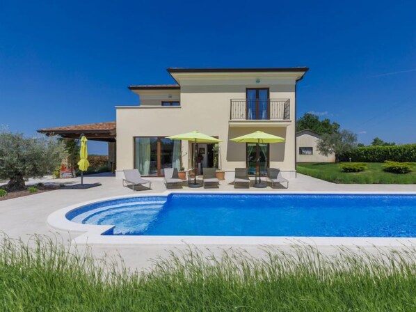 Une maison moderne à deux étages, dotée d’une piscine, d’un espace extérieur aménagé et d’un jardin bien entretenu.