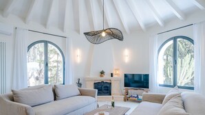 Ett modernt vardagsrum med en öppen spis, en tv och ett stort fönster.