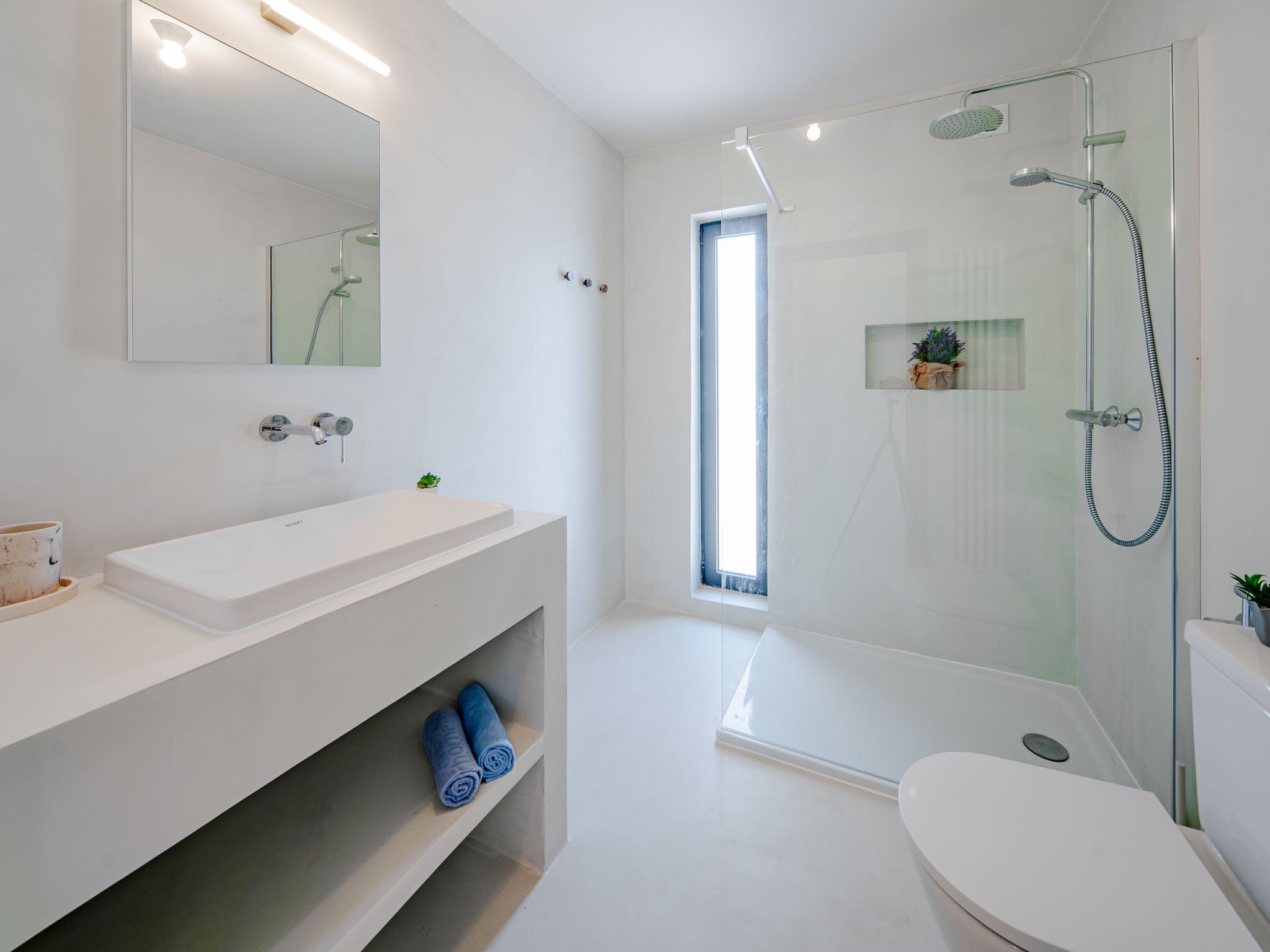 Ein modernes Badezimmer mit einer Duschkabine, einem weißen Waschbecken und einer Toilette.