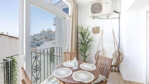 A balcony with a table set for two, a hanging chair, and a potted plant. - Puerto Banus OPQ by Interhome (Marbella)