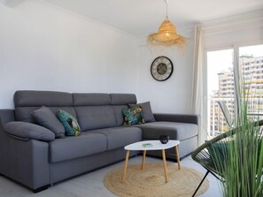 En moderne stue med en grå sofa, et lille hvidt bord og en hængende lampe.