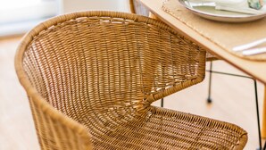A wicker chair and table set in a room with a wooden floor and a window with blinds. - Premium Pestana Apartments (Porto)