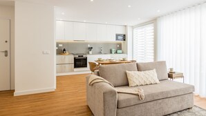 A modern living room with a sofa, a dining table, and a kitchen in the background. - Premium Pestana Apartments (Porto)