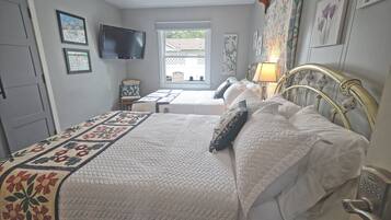 A bedroom with a bed, a television, a window, and a door.
