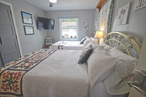 Un dormitorio con cama, televisión, ventana y puerta.