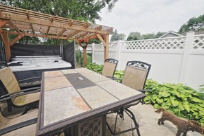 Un patio exterior con una mesa y sillas, una pérgola y una valla blanca.