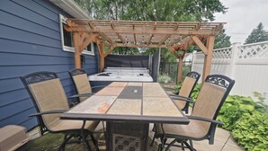 A patio with a wooden pergola, a table, and chairs. - King room in Bed and Breakfast - And A Hot Tub! (FRANKENMUTH)