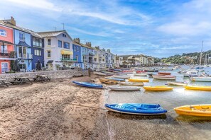 A coastal town with colorful buildings, a sandy beach, and boats docked in the water. - Coombe Bank (Teignmouth)