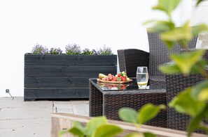 A wicker outdoor seating area with a fruit bowl and a glass of drink. - Coombe Bank (Teignmouth)