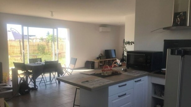 A kitchen with a dining area, a TV, and a refrigerator. - Charmante Maison Calme Toutes Commodités Proche de Tout ! (AUROS)