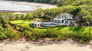 Ein Anwesen am Strand mit Golfplatz, Schwimmbad und üppiger Bepflanzung.