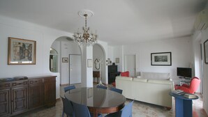 A spacious living area with a dining table, blue chairs, a cream-colored sofa, a red armchair, and a chandelier. - PescarHeart Apartment in the heart of Pescara (Pescara)