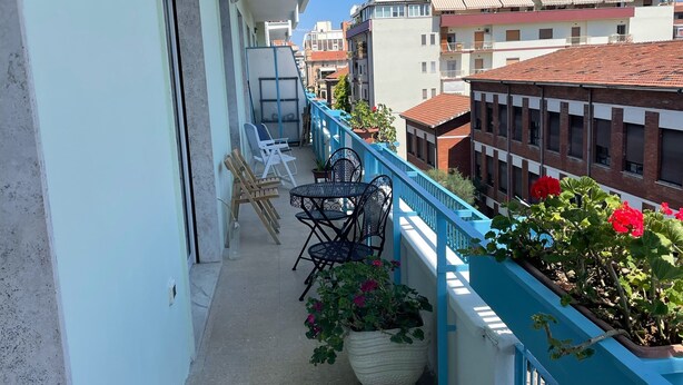 A balcony with a blue railing, potted plants, and outdoor furniture. - PescarHeart Apartment in the heart of Pescara (Pescara)