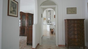 A hallway with a wooden cabinet, a framed picture, and a kitchen in the background. - PescarHeart Apartment in the heart of Pescara (Pescara)
