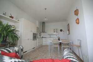 Une cuisine moderne avec des meubles blancs, un four encastré et un coin repas comprenant une table et des chaises.