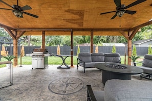 Une terrasse extérieure équipée d’un barbecue, de sièges et d’un motif de boussole incrusté dans le sol.