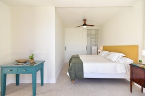 Un dormitorio con cama, escritorio, armario y ventilador de techo.