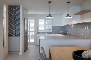 A modern kitchen with a central island, pendant lighting, and a view to the outside.
