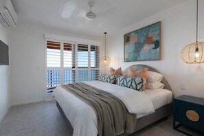A bedroom with a bed, a ceiling fan, a painting, and a window with blinds.