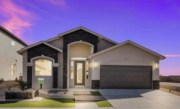 Enter through a welcoming archway into this two-story home with a manicured front yard and garage.