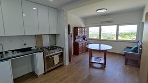 Uma cozinha moderna com armários brancos, fogão a gás e uma área de jantar com mesa redonda.