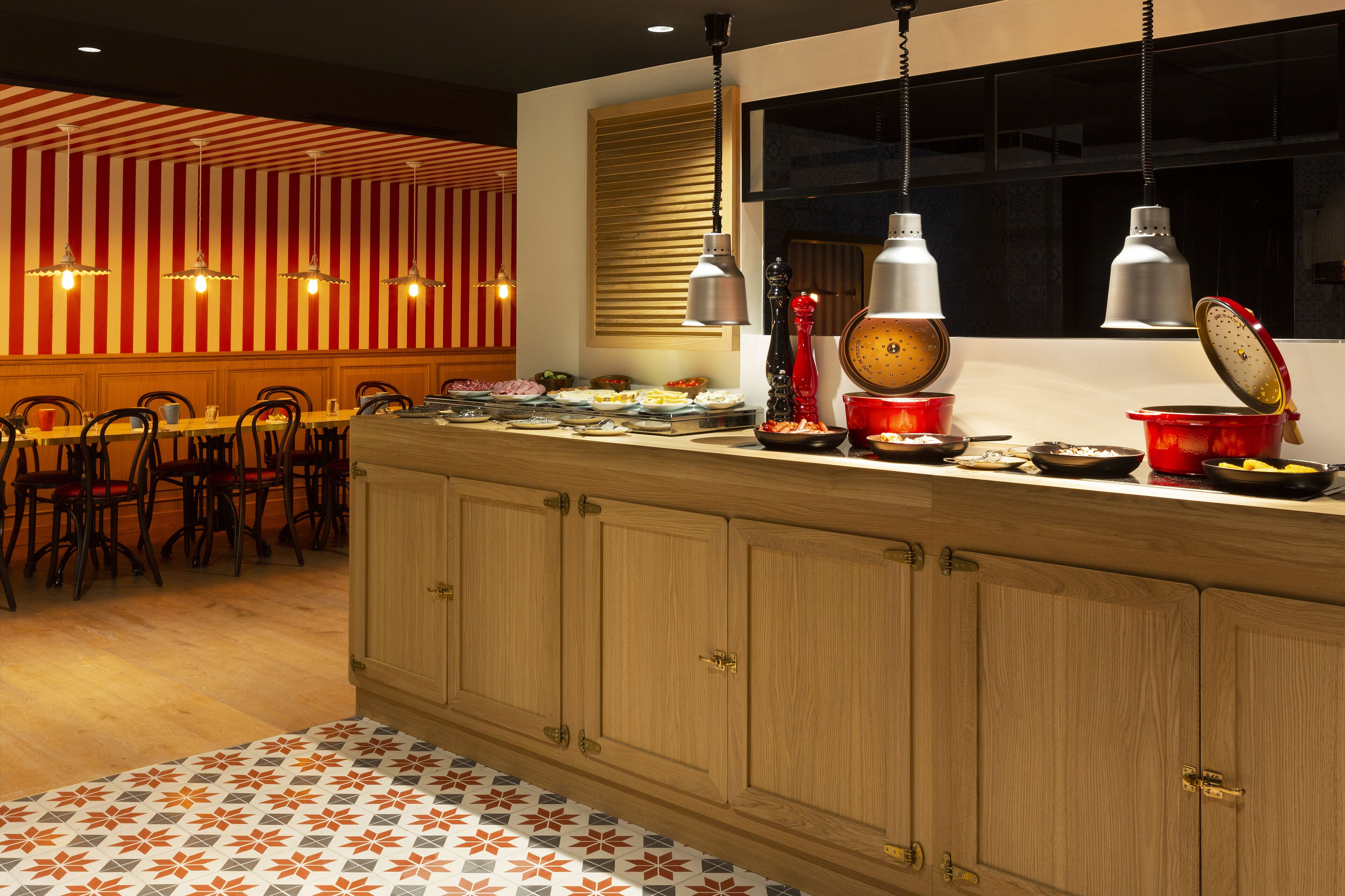 Una cocina moderna con armarios de madera, un comedor con sillas e iluminación colgante.