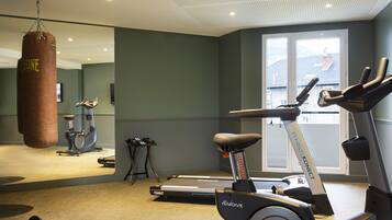 Une salle de sport équipée d’un sac de frappe, de tapis de course et d’haltères.