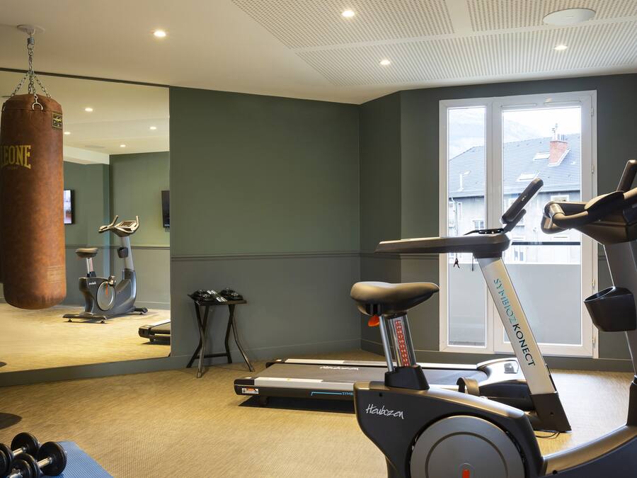 Une salle de sport équipée d’un sac de frappe, de tapis de course et d’haltères.