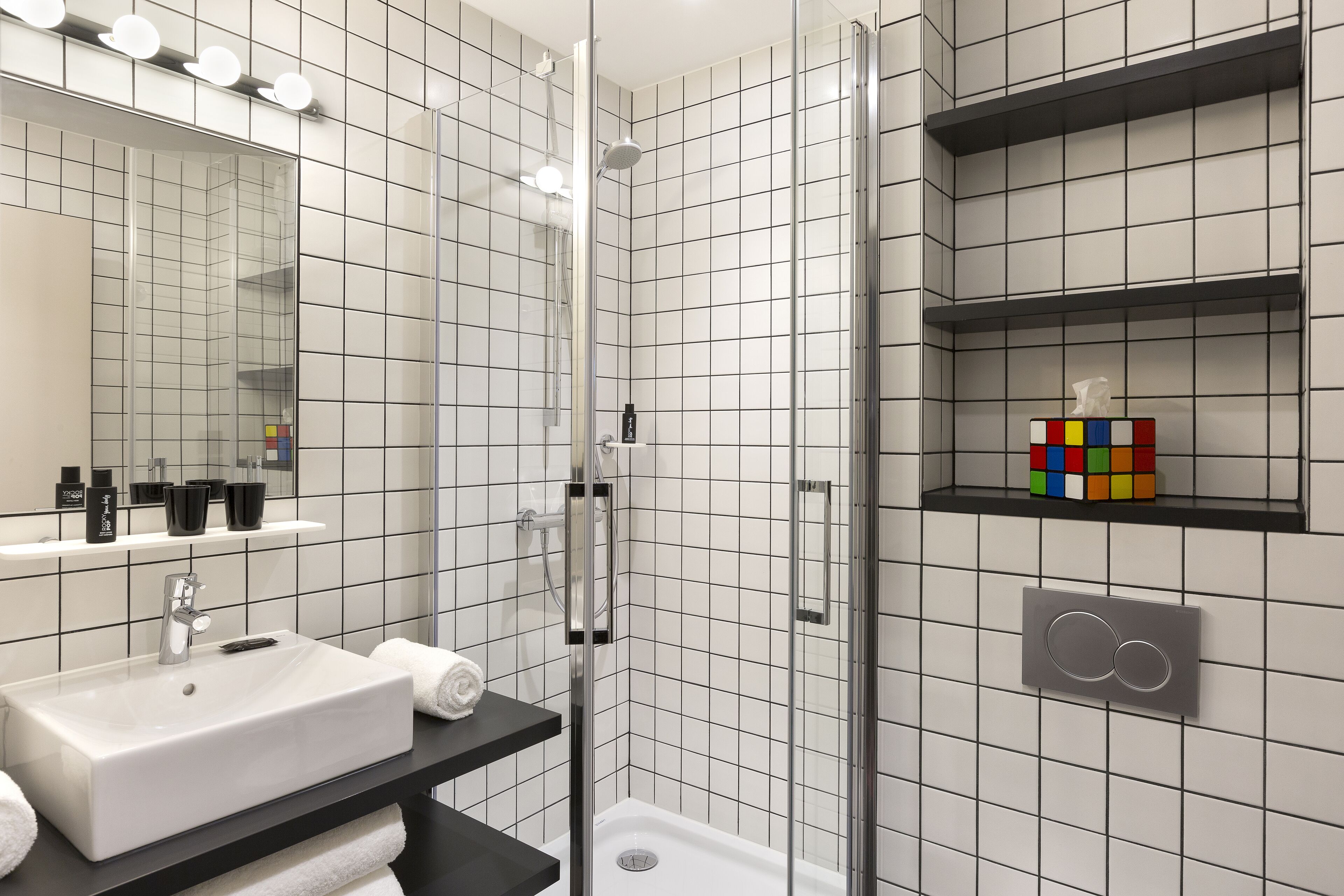 A modern bathroom with a white sink, mirror, and tiled walls.