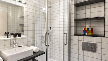 A modern bathroom with a white sink, mirror, and tiled walls.