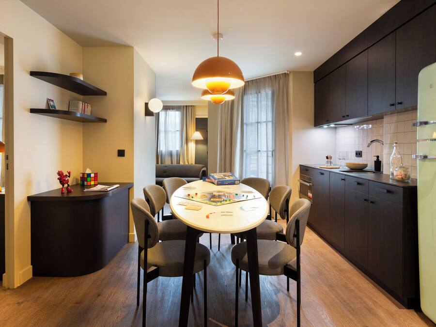 Una cocina moderna con una mesa de comedor, sillas y un refrigerador.