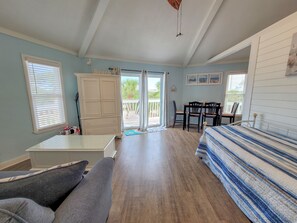 A room with a bed, a desk, a chair, a wardrobe, and a balcony with a view.