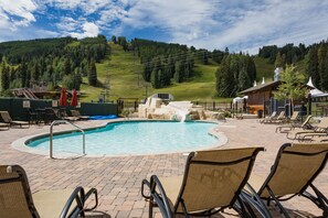 Ein Swimmingpool mit Liegestühlen und einem Sessellift im Hintergrund.