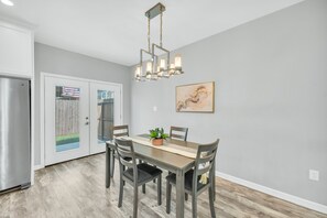 A modern kitchen with a dining table, chairs, a chandelier, and a refrigerator. - 🍊 Home Away from Home (Houston)